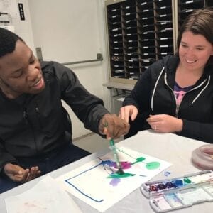 Adult special needs student drawing with teacher